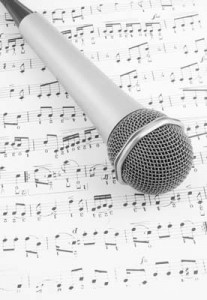 A microphone resting on sheet music, symbolizing singing and musical performance.